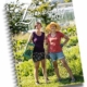Two gardeners stand in a sunny garden with baskets and a hoe, on a spiral calendar cover reading 'Landkalender 2027' (Danish/Norwegian style).