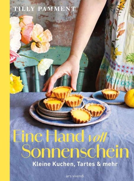 Book cover showing a hand arranging lemon tarts on a blue tablecloth with flowers in the background; title 'Fine Hand voll Sonnenschein' and author 'Tilly Pamment' visible.
