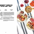 Open cookbook spread: left page shows a German recipe with a bold title, right page a top-down photo of a meal with sliced beef, roasted vegetables, bowls, and wine glasses on a striped tablecloth.